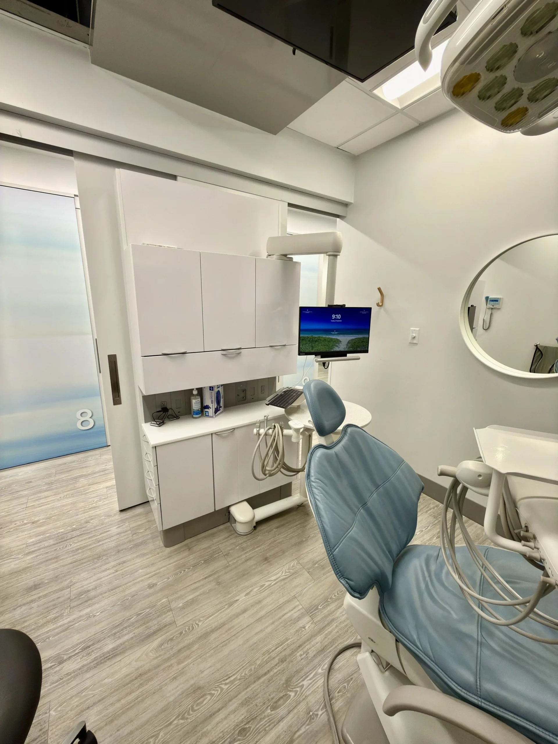 Dental operatory with a blue chair, white ADEC cabinetry and a sink