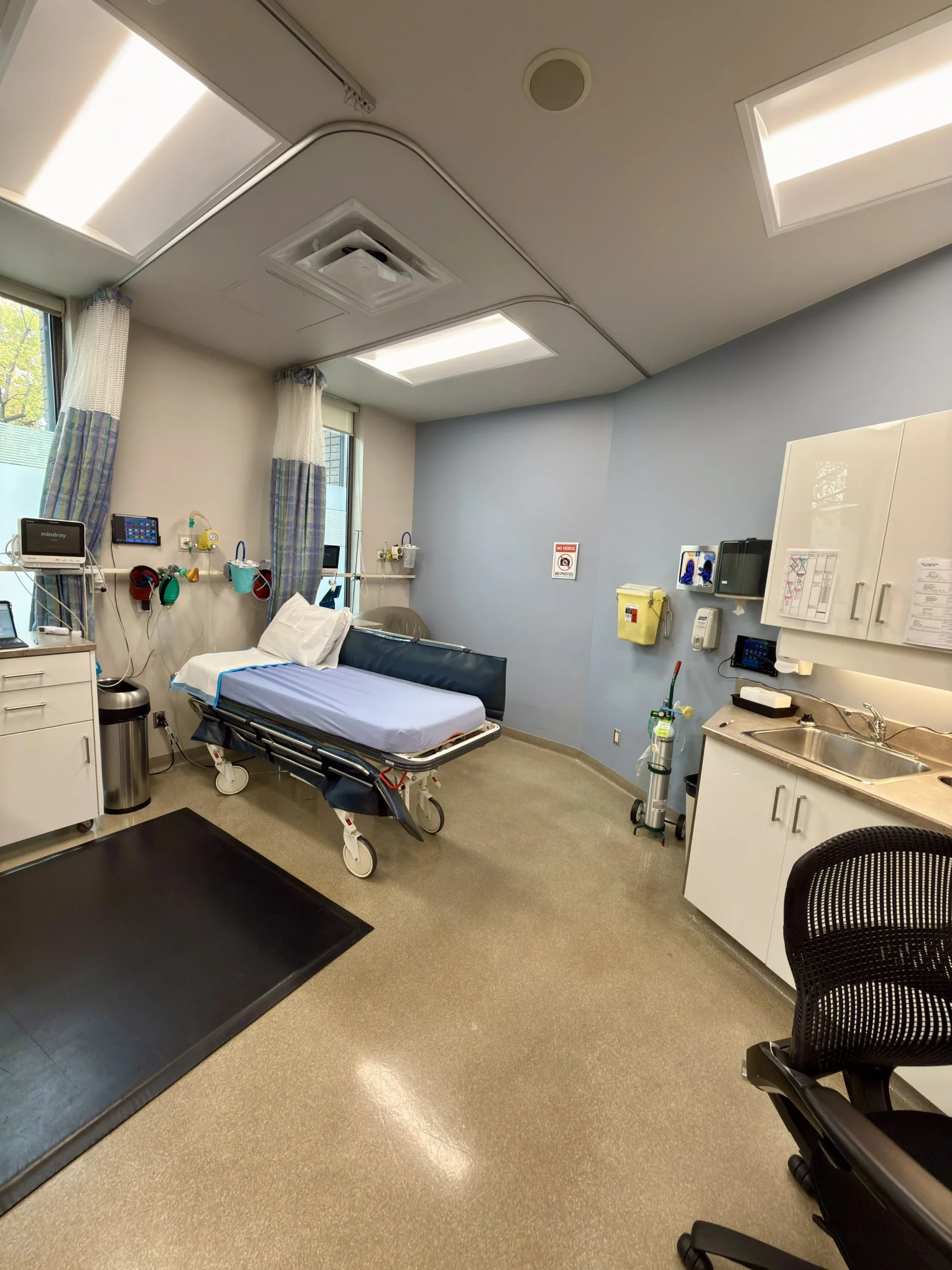 Recovery room with a patient gurney and wall-mounted monitoring equipment