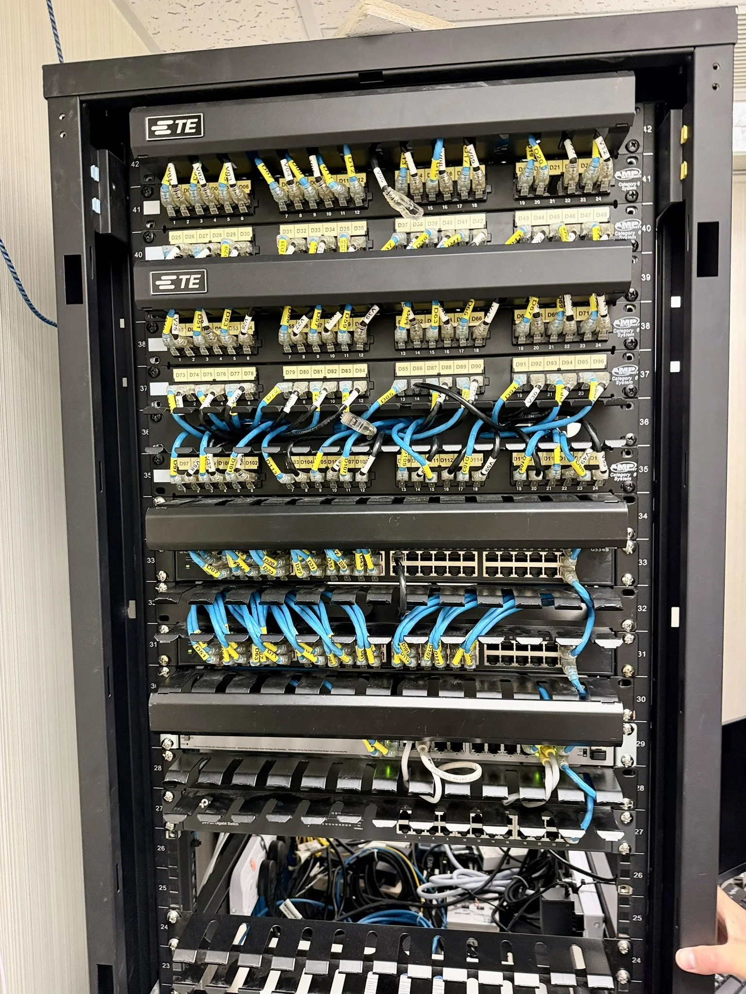 Server rack with switches and neatly combed yellow and blue patch cables