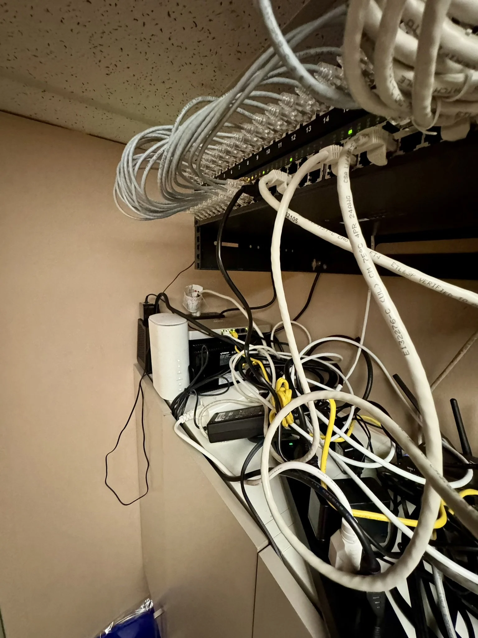 Messy bundle of network cables hanging from a shelf before cleanup