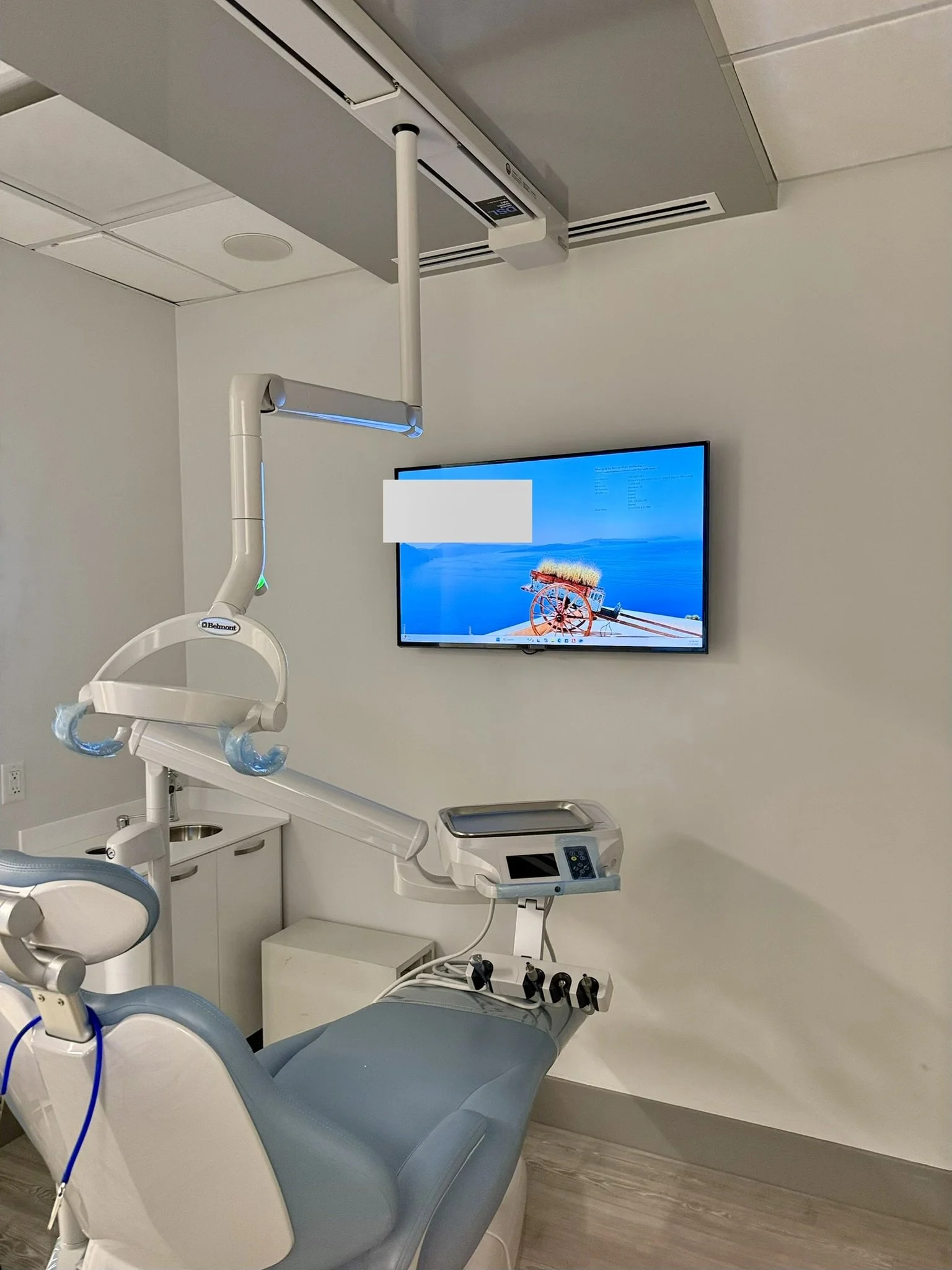 Dental treatment room with a large wall-mounted display above the chair